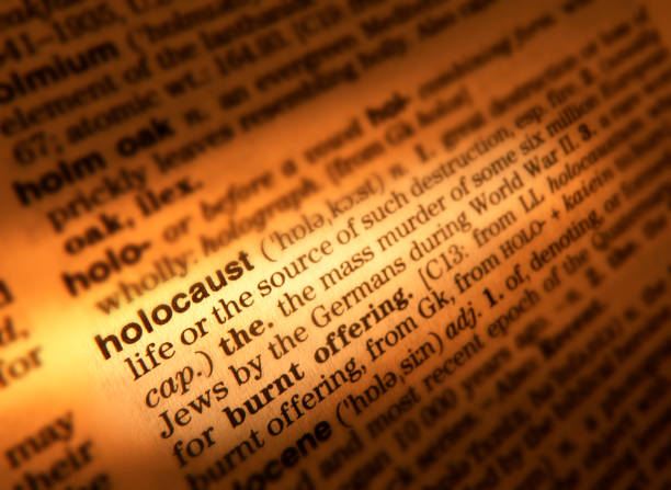 DICTIONARY PAGE SHOWING DEFINITION OF THE WORD HOLOCAUST CLOSE UP OF DICTIONARY PAGE SHOWING DEFINITION OF THE WORD HOLOCAUST holocaust stock pictures, royalty-free photos & images