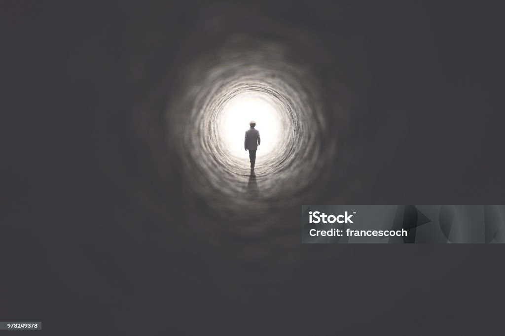 man getting out of a dark tunnel toward light Tunnel Stock Photo