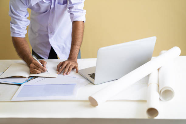 istock Architect man working with laptop and blueprints, Engineer inspection in workplace for architectural plan, Sketching a construction project, Business concept 978250416