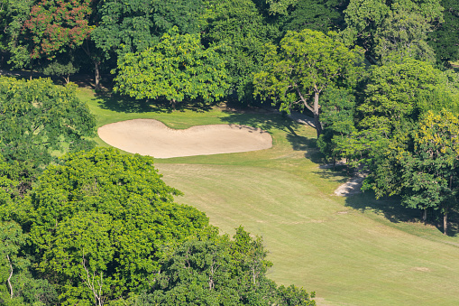 Landscape in aerial view of golf course for golfer with grass green field, putting green and bunkers and nature forest