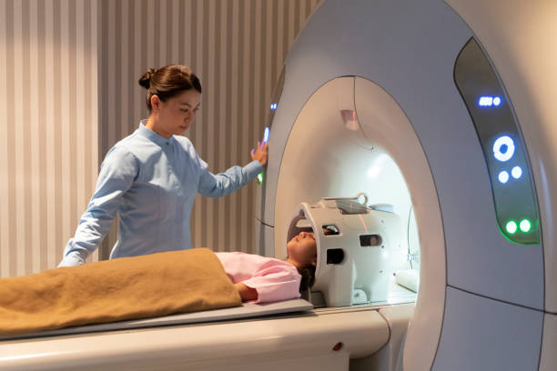 chica acostado en cama de resonancia - mri scanner fotografías e imágenes de stock