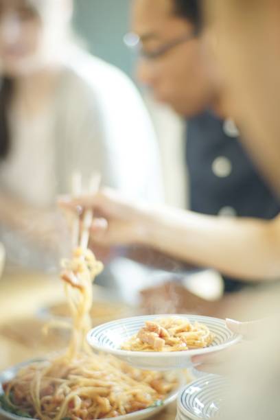 istock Woman putting spaghetti in a dish with chopsticks at Japanese pub 978268086