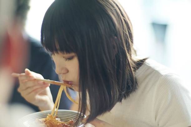 Woman eating spaghetti with chopsticks at Japanese pub