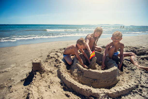 istock Three kids are building a sandcastle on spanish beach 978271330