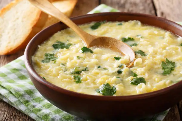 Photo of Italian egg cream soup stracciatella with farfalline pasta and cheese close-up. horizontal