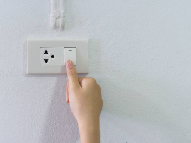 istock Close up female hand turning on or off on grey light switch with texture background. Turning light concept. 978277312