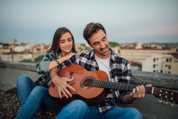 istock Pretty young couple playing a guitar on a roof 978296042