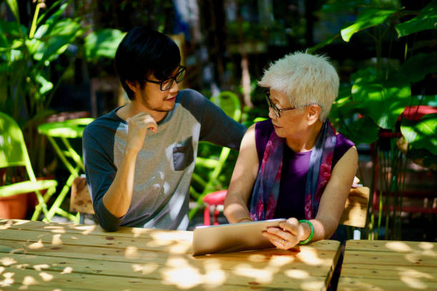 istock Asian Son teaching Mother how to use a digital tablet 978299378
