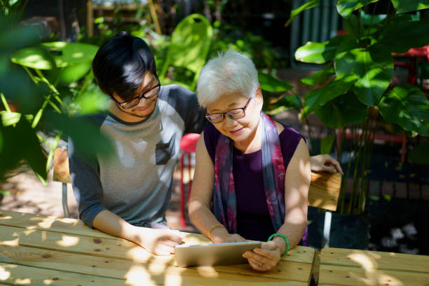 istock Asian Son teaching Mother how to use a digital tablet 978299444