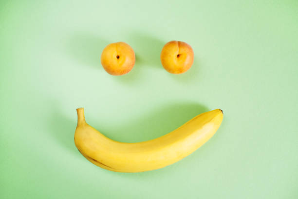 istock Two apricots and one banana on green background as smiley. 978304326