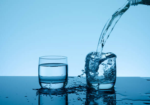 istock Creative splashing water in the glass on blue background 978305256
