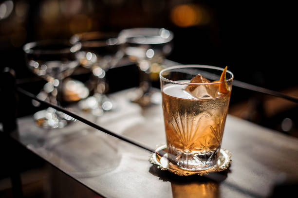 frais d’été façonné vieux cocktail avec glace et zeste d’orange - whisky alcohol glass image photos et images de collection