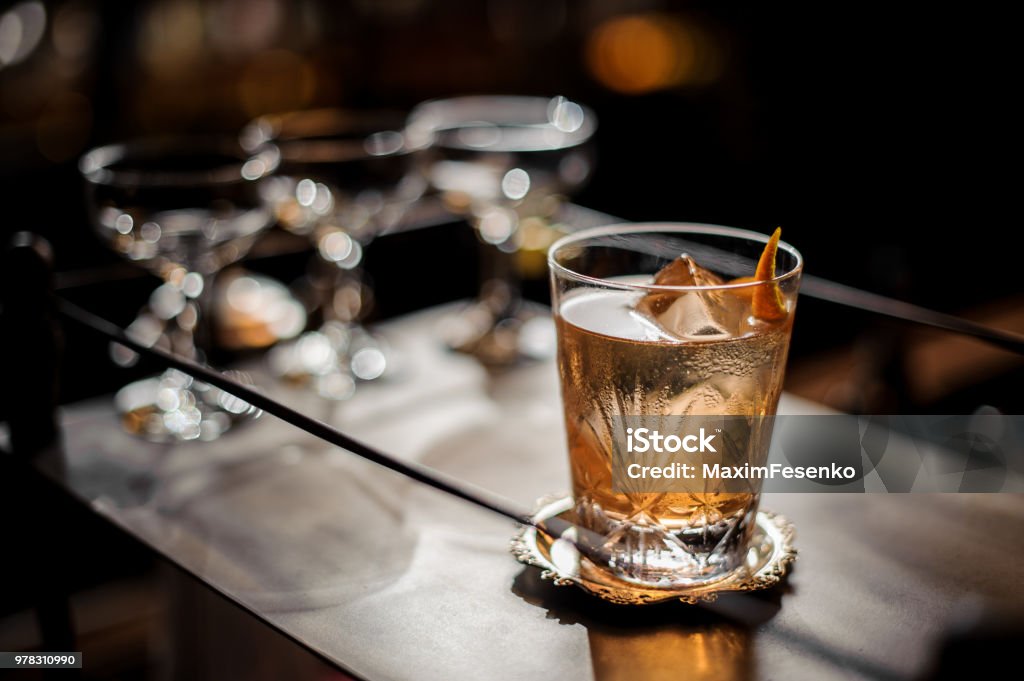 Fresh old fashioned summer cocktail with ice and orange peel Fresh and tasty old fashioned summer cocktail with ice and orange peel on the vintage brown background Cocktail Stock Photo