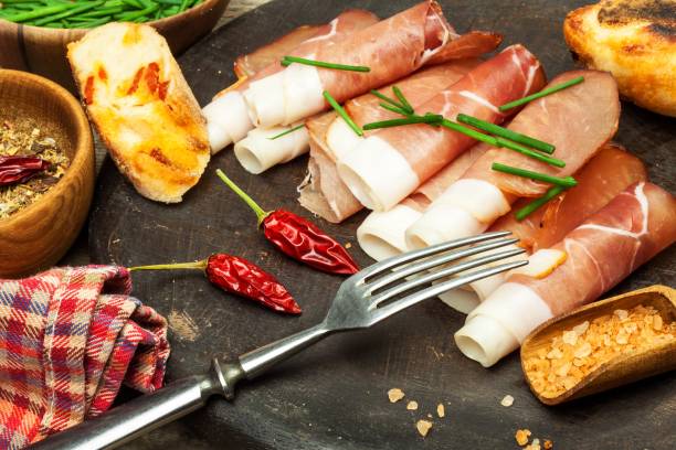 istock Thinly sliced German black forest ham with sliced ciabatta bread. Sliced and smoked ham with schwarzwald ham or prosciutto. Traditional German food. 978314912