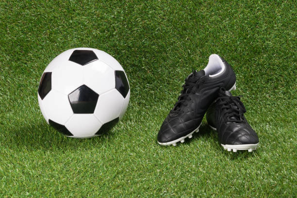 istock Soccer ball and boots on a green artificial turf 978320842