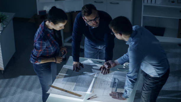istock Late at Night Team of Design Engineers Work with Drafts and Documents on Illuminated Table. 978339226