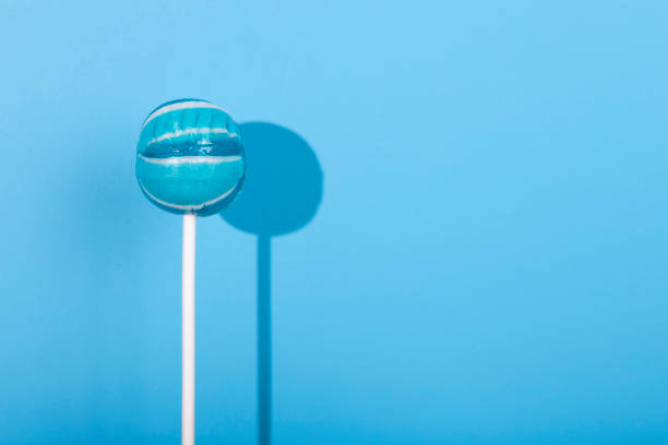 Blue Lolipop candy with shadow on pastel blue background. Minimal style concept. New Minimalism. Punchy Pastels