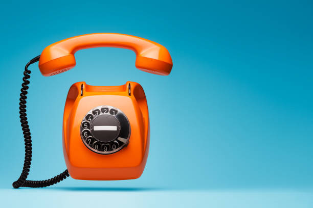 istock Old orange telephone rings with handset off. 978347442