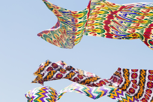 Waving in sky fabric. Multicolored silk textile materials fluttering against the blue sky.