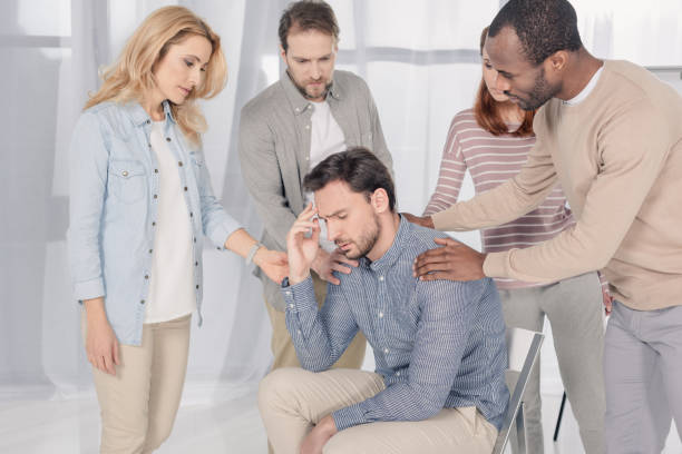 istock mid adult multiethnic people supporting upset man during group therapy 978360304