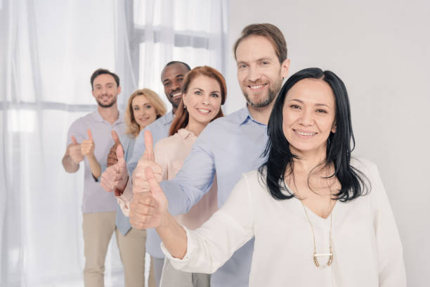 istock middle aged people smiling at camera and showing thumbs up during group therapy 978361134