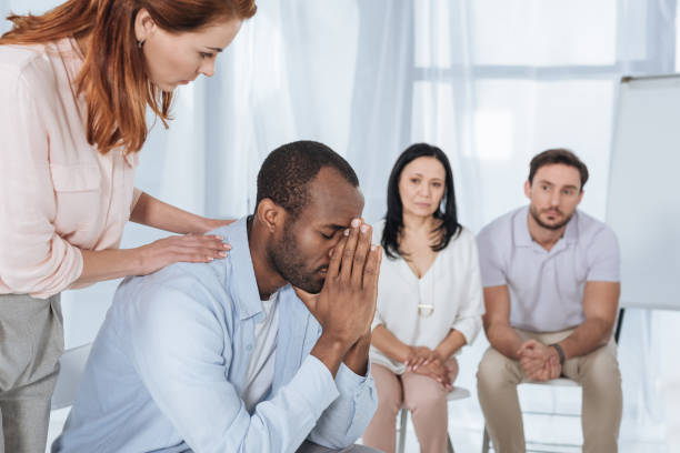 istock middle aged people supporting upset african american man during anonymous group therapy 978361360