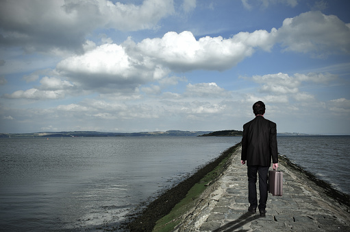 Businessman walking on the pier over sea