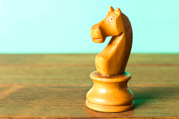 istock Chess horse on a wooden table. On a turquoise background. Close up 978371598