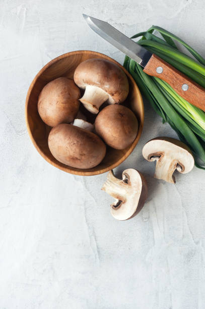 istock Sliced brown champignons on concrete background. Vertical photo. 978375728