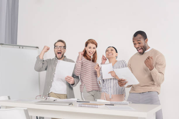 istock happy multiethnic middle aged people holding papers and triumphing 978378370
