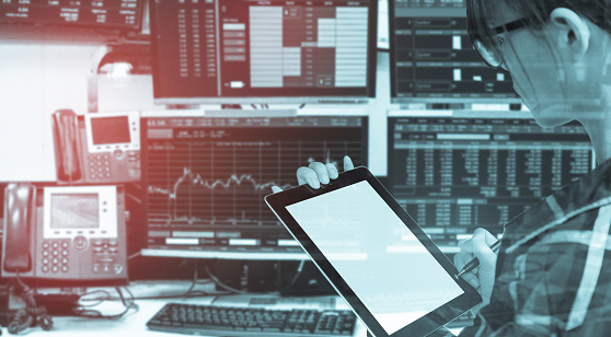 Double exposure of business woman holding tablet for Stock market quotes and chart in monitor computer room with business office equipments .business and money trading concept,panorama photo.