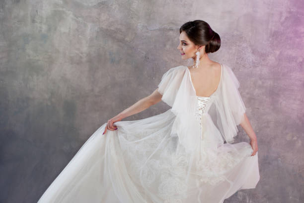 istock Beautiful and stylish bride in wedding dress in Studio on grey textured background 978383380