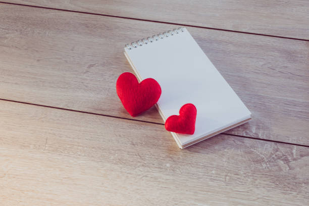 istock Red heart shape and notebook on wooden board. 978459398