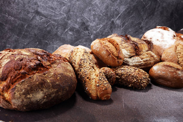 istock Different kinds of bread and bread rolls on board from above. Kitchen or bakery 978461964