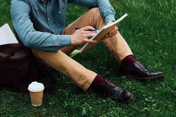 istock cropped shot of young man writing in notebook while sitting on grass 978461984