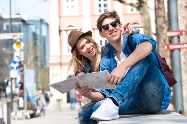 istock Young travelers sitting outdoors with coffee cups and a map 978462374