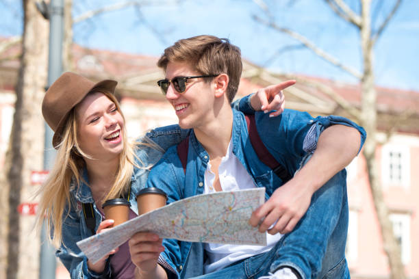 istock Young travelers sitting outdoors with coffee cups and a map 978462384