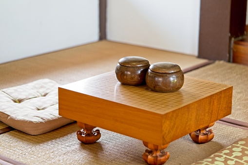 China, Japón, Coreano juego de GO. Go o wei-Chi - tradicional juego de mesa Asia WeiQi. Tablero de juego ir vacío con piedra negro y blanco en un recipiente en la habitación de estilo japonés photo
