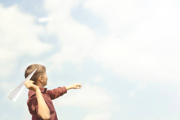 young boy has fun in throwing paper airplanes in the sky