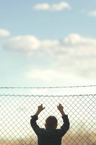 istock young boy looks out from the net towards freedom 978498846
