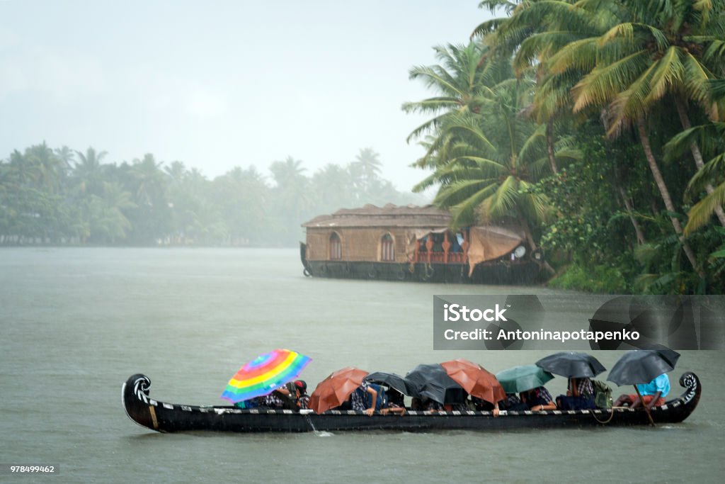 Monsoon time. People crossing a river by boat in rain Monsoon time. People crossing a river by boat in rain with umbrellas Monsoon Stock Photo