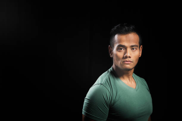 Pensive Muscular Asian man portrait with black background