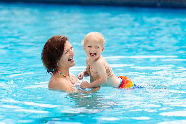 мать и ребенок в бассейне - mother exercising baby child стоковые фото и изображения