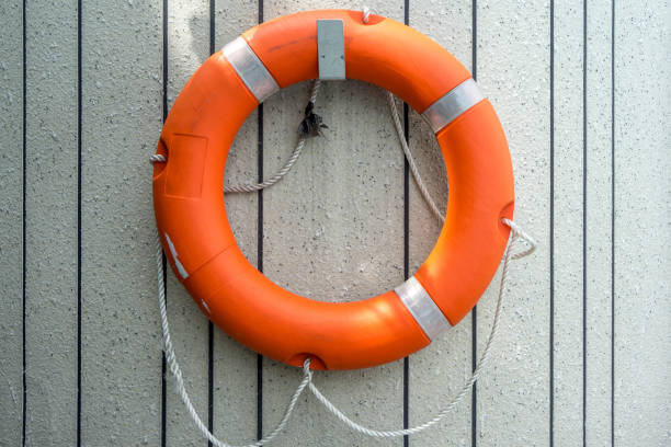 istock Orange Lifebuoy hanging on stone cement wall 978513212
