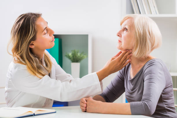 Doctor examines patient's throat Female doctor examines her senior patient's throat in office. lymph node photos stock pictures, royalty-free photos & images
