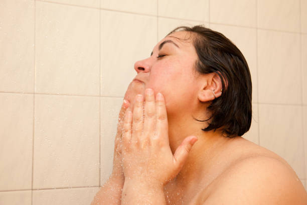 istock Woman washes face in shower 978520872