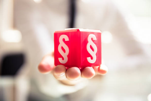 Close-up Of A Person's Hand Holding Red Cubic Block With Paragraph Symbol