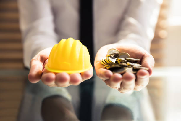 istock Human Hand Holding Hardhat And Many Golden Coins 978523556