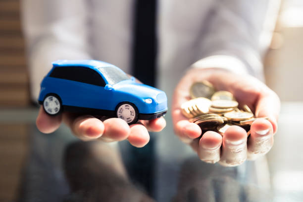 Businessperson Holding Small Blue Car And Golden Coins Close-up Of A Businessperson's Hand Holding Small Blue Car And Golden Coins cash for cars stock pictures, royalty-free photos & images