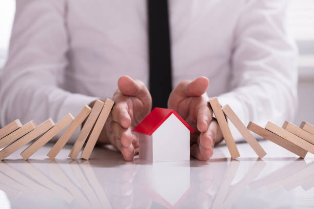 istock Businessperson Protecting House Model From Falling Wooden Blocks 978525250